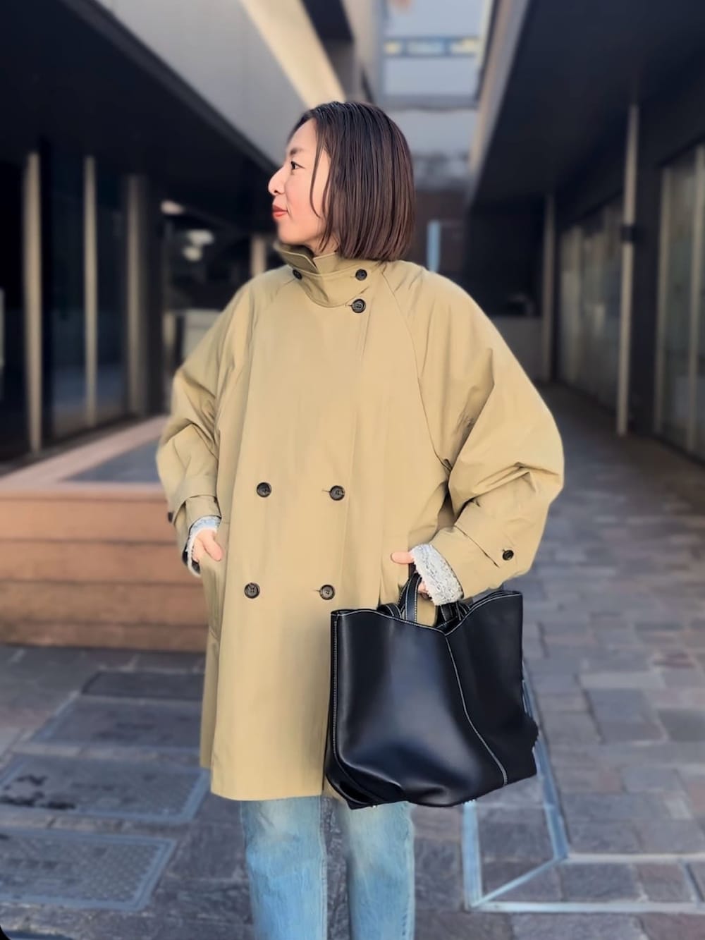 ベージュ系のトレンチコート、ブルー系のデニムパンツ、ブラック系のローファーを着用したレディースの冬コーディネートの5枚目の写真