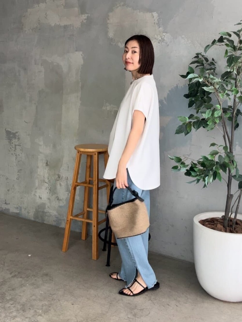 ブルー系のデニムパンツ、ブラック系のサンダル、ホワイト系のハンドバッグを着用したレディースの春コーディネートの2枚目の写真