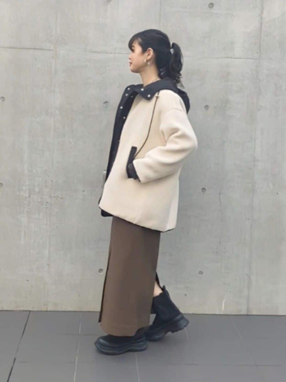 グレー系のスウェット、ブラウン系のスカート、ブラック系のブーツを着用したレディースの秋コーディネートの2枚目の写真