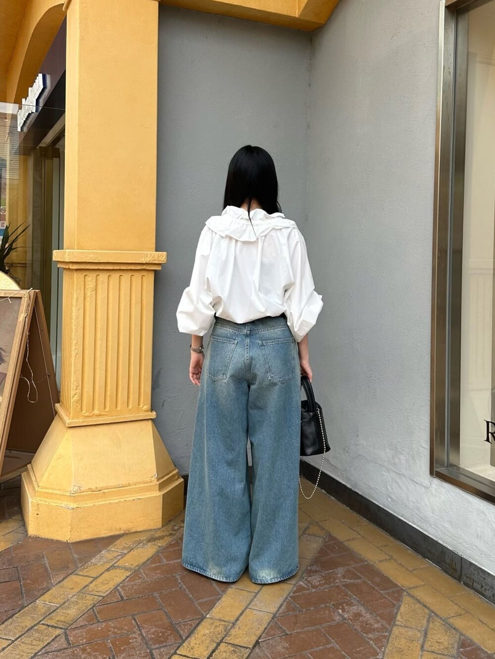 ホワイト系のシャツ/ブラウス、ブルー系のデニムパンツ、ブラック系のハンドバッグを着用したレディースの夏コーディネートの3枚目の写真