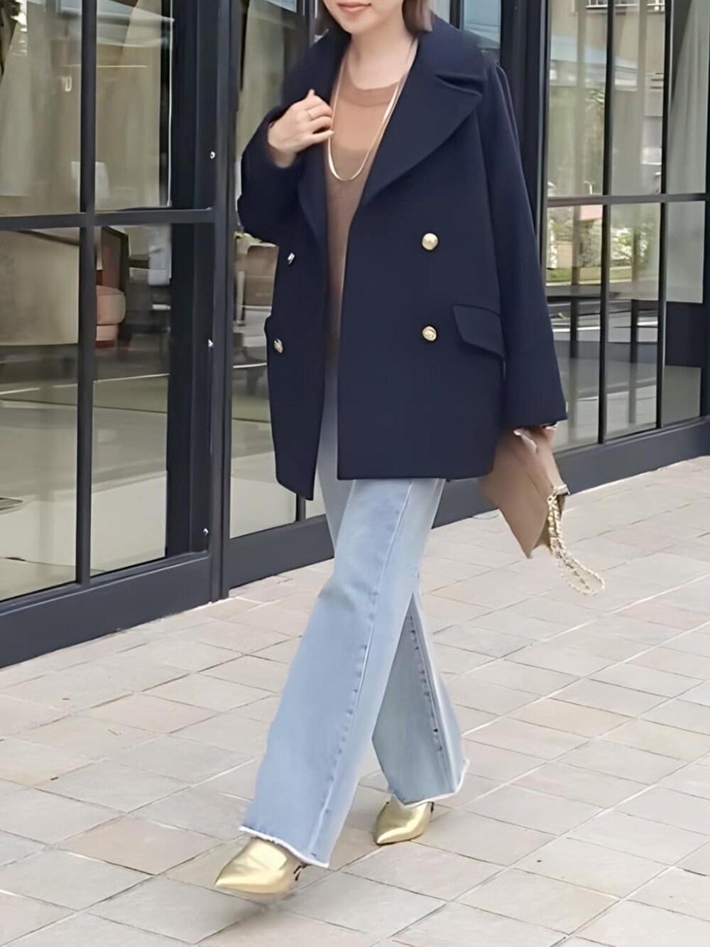 ブルー系のピーコート、ブルー系のデニムパンツ、ゴールド系のパンプスを着用したレディースの冬コーディネートの5枚目の写真