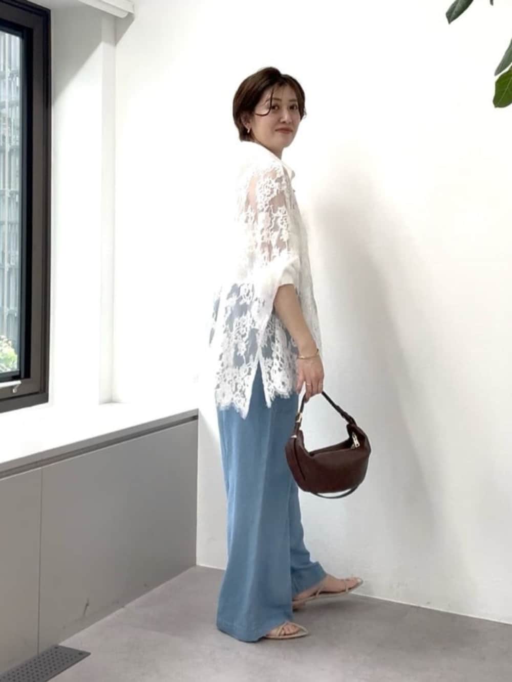 ベージュ系のサンダル、ブラウン系のショルダーバッグ、ブルー系のデニムパンツを着用したレディースの夏コーディネートの2枚目の写真