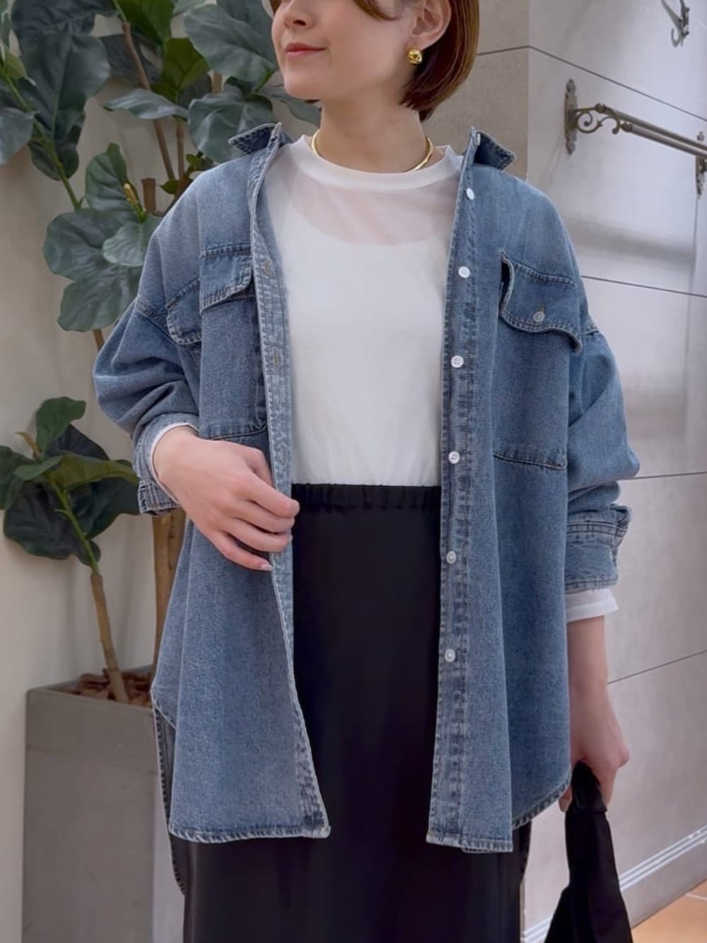 ブルー系のシャツ/ブラウス、ブラック系のスカート、グリーン系のハンドバッグを着用したレディースの冬コーディネートの4枚目の写真