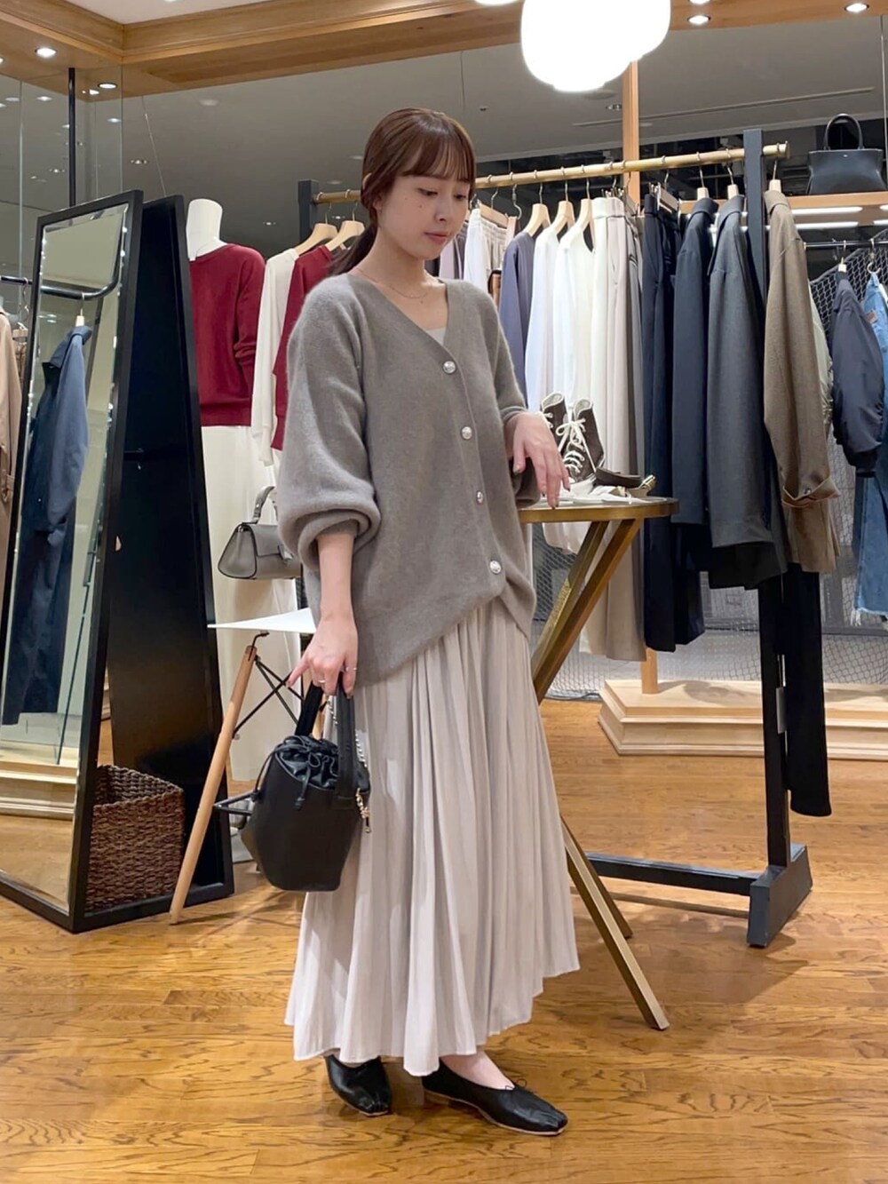 ブラウン系のカーディガン/ボレロ、ベージュ系のスカート、ブラック系のハンドバッグを着用したレディースの冬コーディネートの3枚目の写真