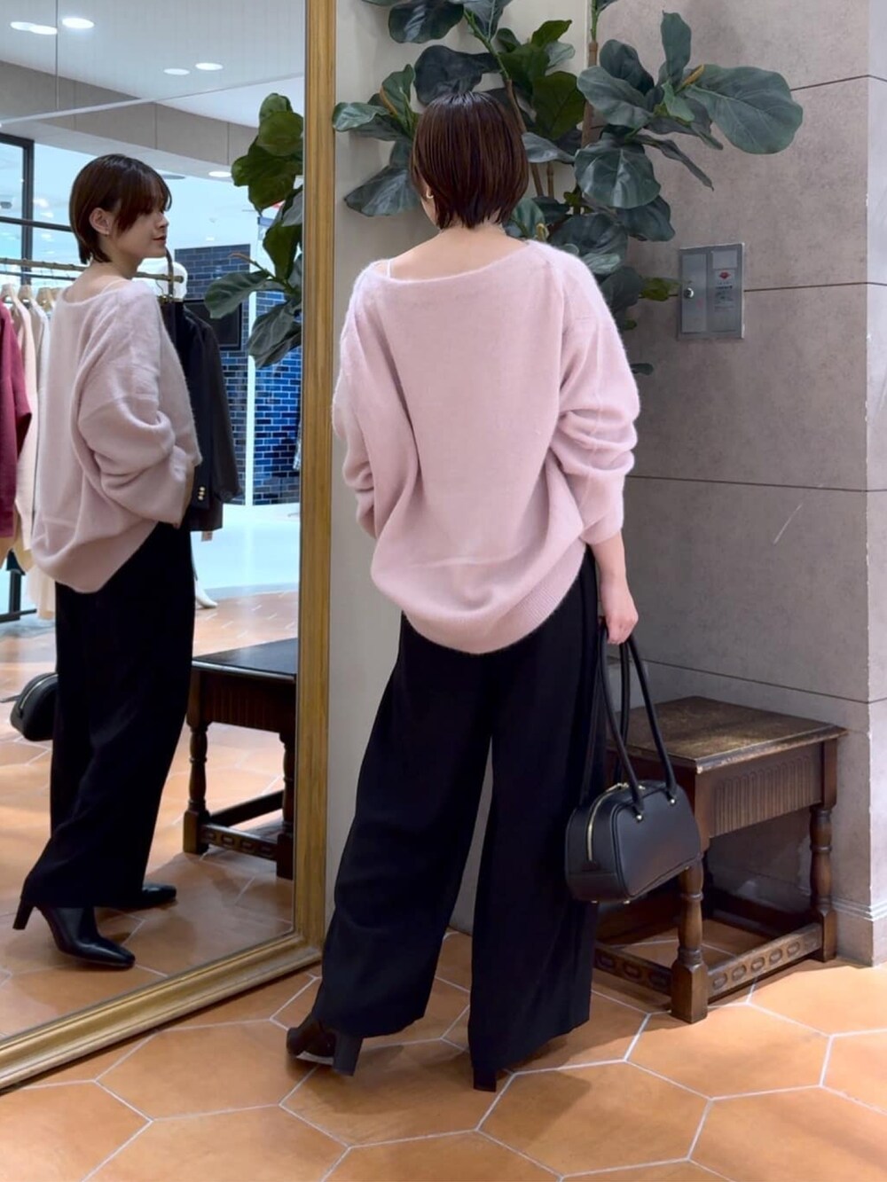 ピンク系のニット/セーター、ブラック系のスラックス、ブラック系のショルダーバッグを着用したレディースの冬コーディネートの3枚目の写真