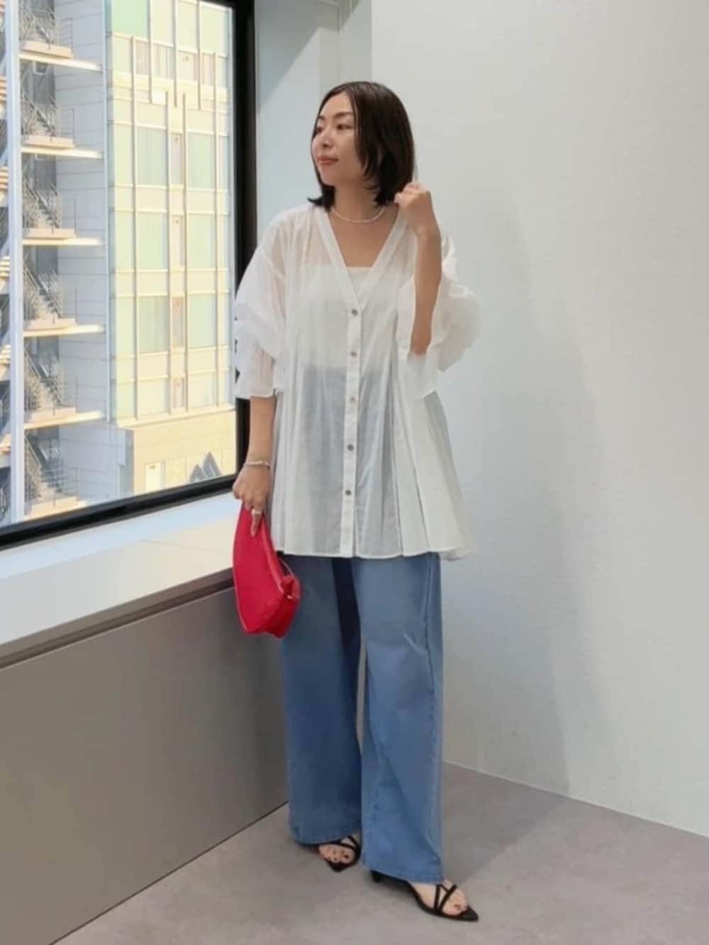 ブラック系のサンダル、ブルー系のデニムパンツ、レッド系のハンドバッグを着用したレディースの春コーディネートの6枚目の写真