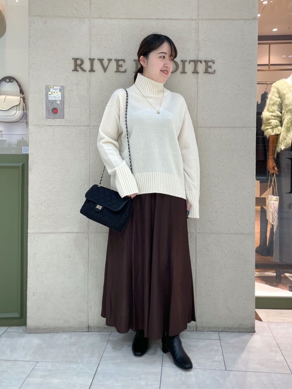 イエロー系のボストンバッグ、ホワイト系のニット/セーター、グレー系のその他アウターを着用したレディースの秋コーディネートの2枚目の写真