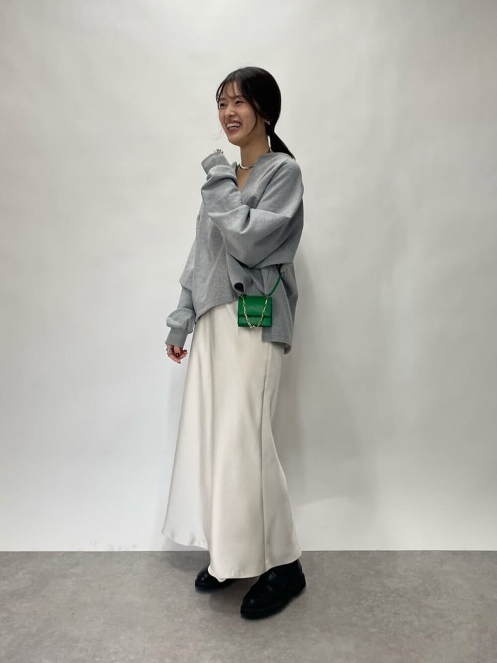 グレー系のスウェット、グリーン系のショルダーバッグ、ベージュ系のスカートを着用したレディースの冬コーディネートの2枚目の写真