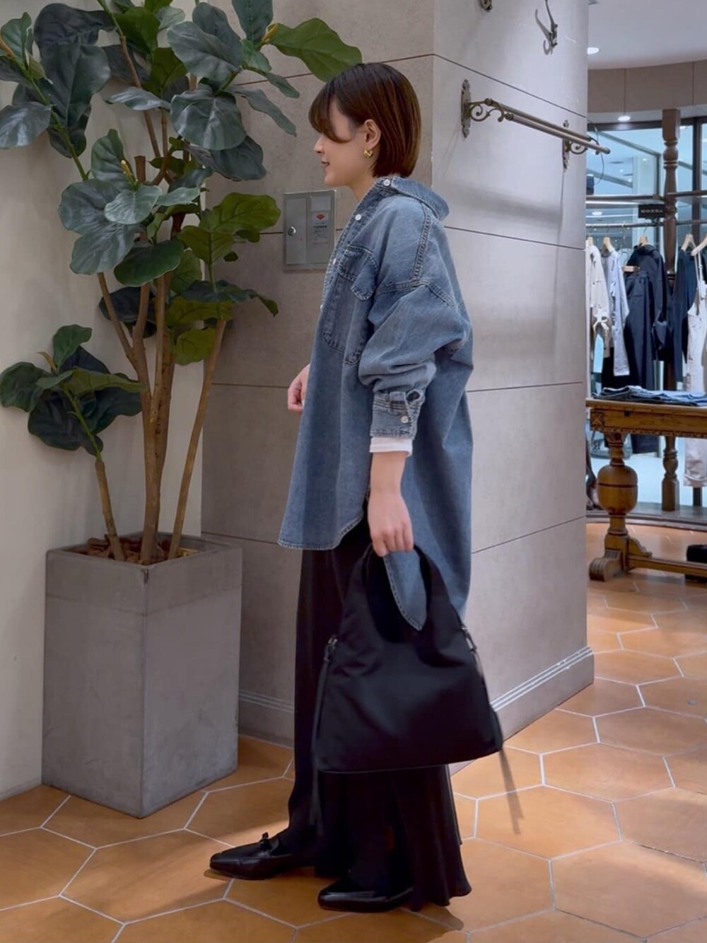 ブルー系のシャツ/ブラウス、ブラック系のスカート、グリーン系のハンドバッグを着用したレディースの冬コーディネートの2枚目の写真