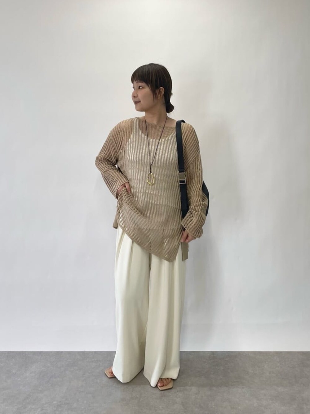 ホワイト系のニット/セーター、ホワイト系のスラックス、ブルー系のサンダルを着用したレディースの春コーディネートの2枚目の写真