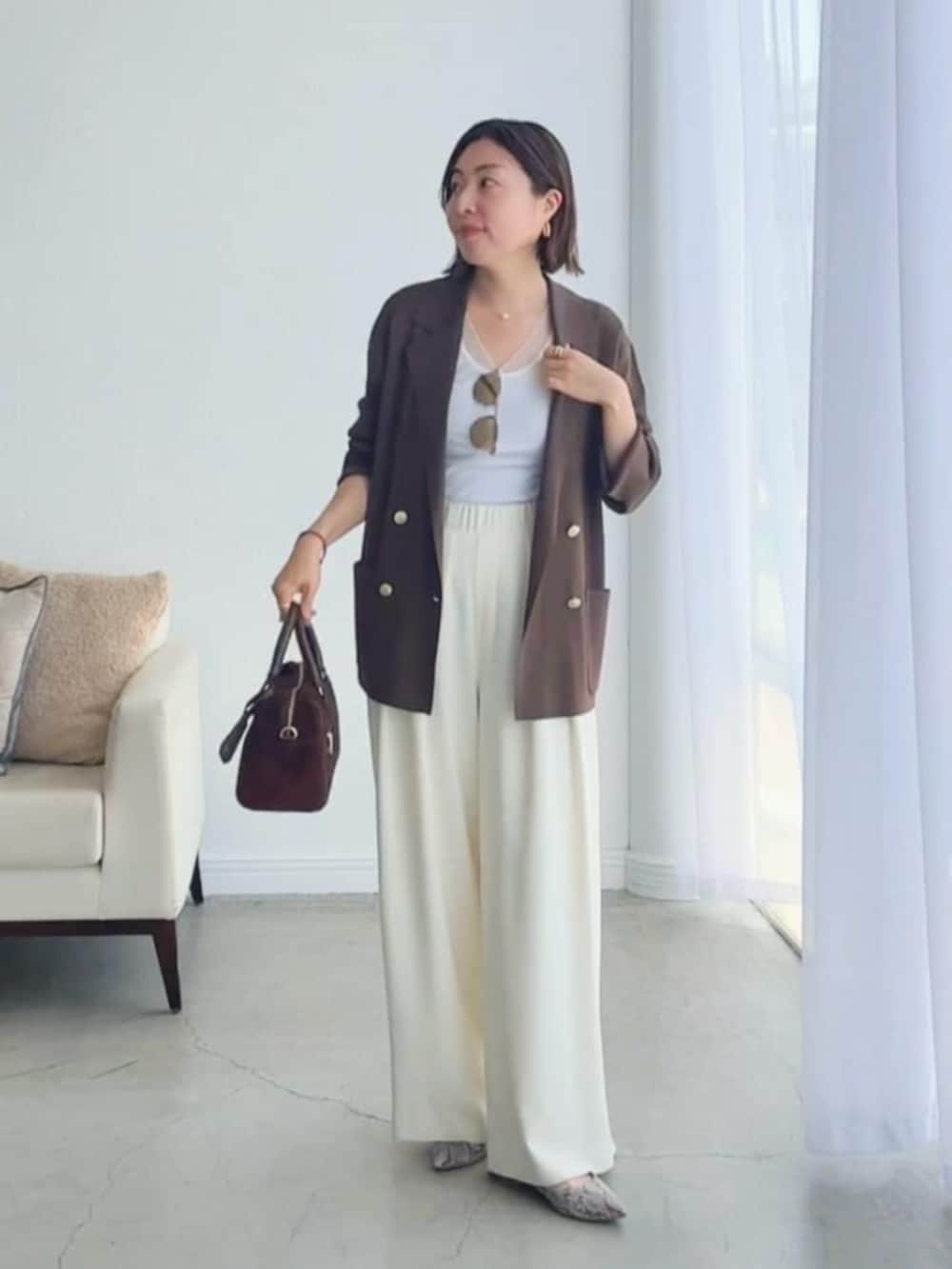 ホワイト系のスラックス、グレー系のパンプス、ホワイト系のキャミソールを着用したレディースの夏コーディネートの6枚目の写真