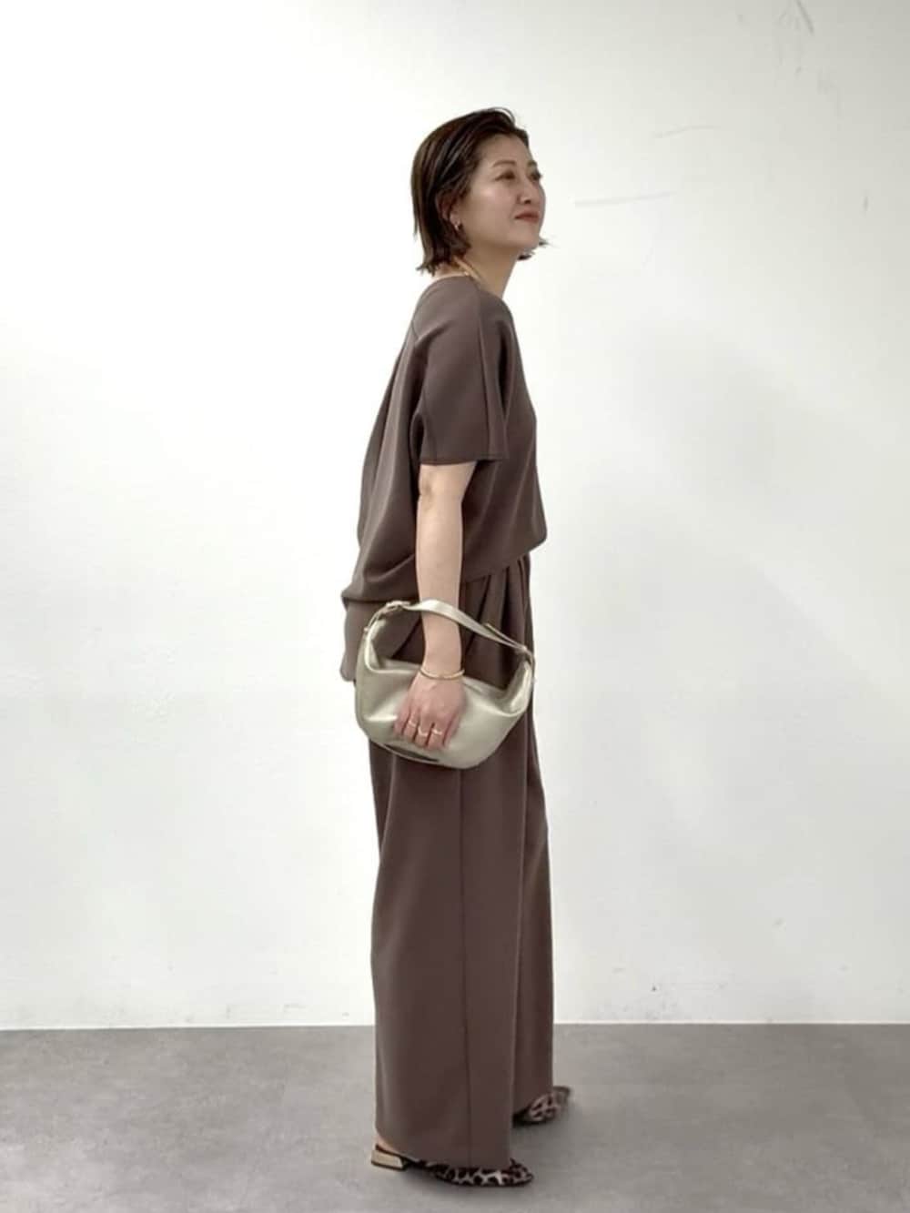 ベージュ系のその他シューズ、ゴールド系のショルダーバッグ、ブラウン系のその他パンツを着用したレディースの春コーディネートの2枚目の写真