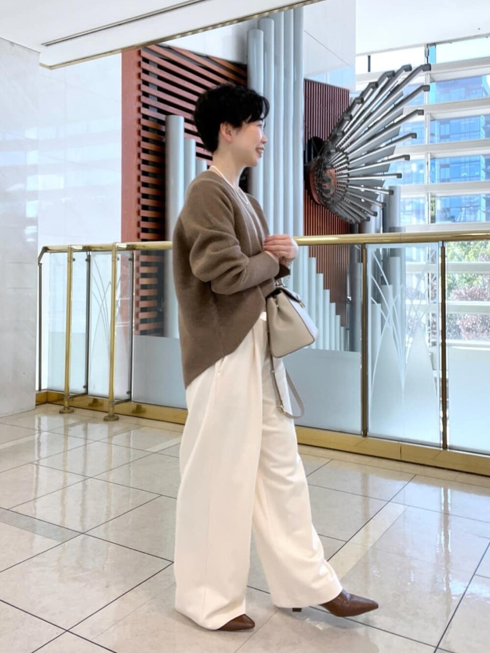 イエロー系のニット/セーター、ホワイト系のその他パンツ、ブラウン系のローファーを着用したレディースの冬コーディネートの4枚目の写真