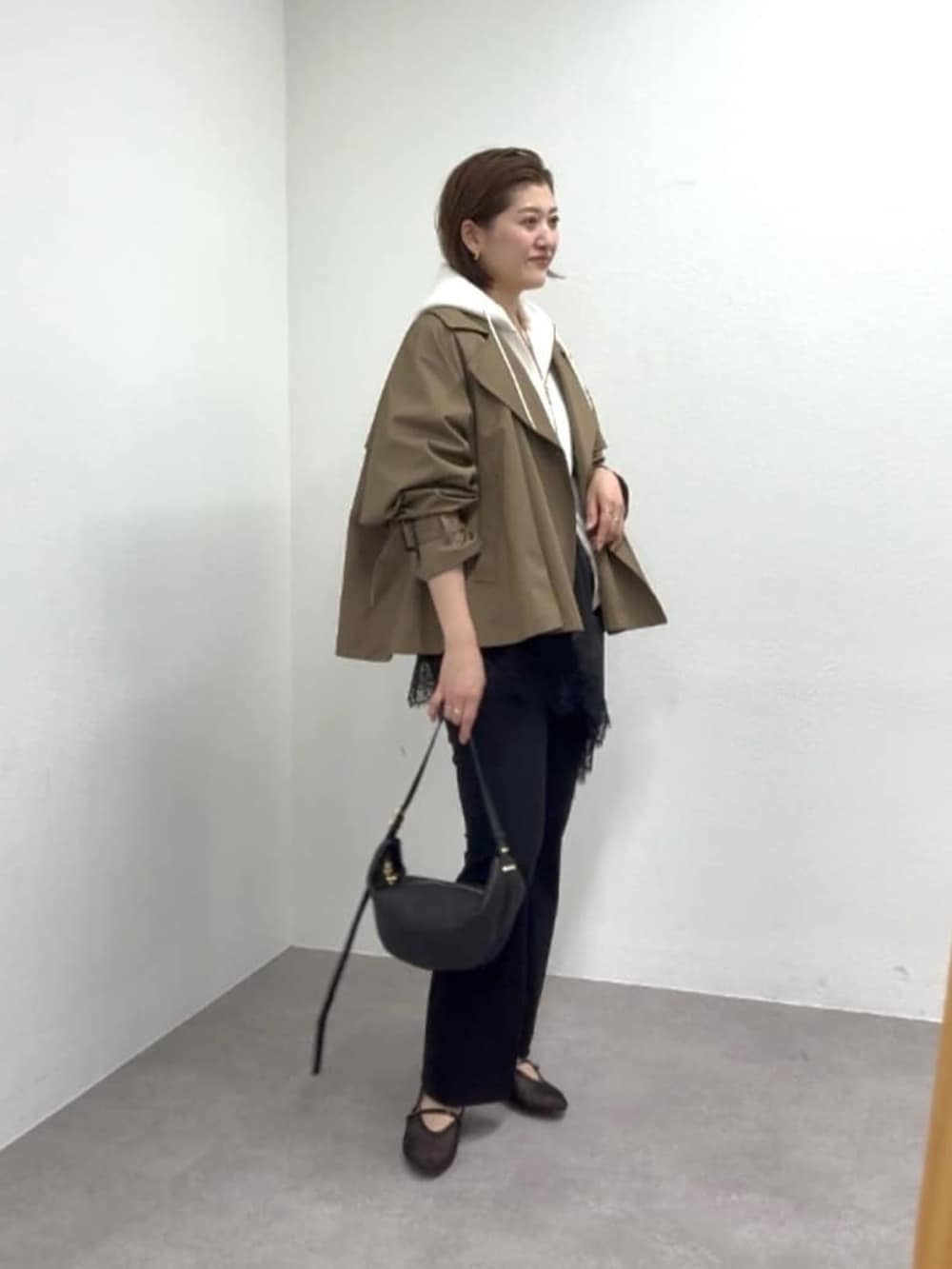 ホワイト系のパーカー、ブラウン系のトレンチコート、ブラック系のその他パンツを着用したレディースの冬コーディネートの2枚目の写真