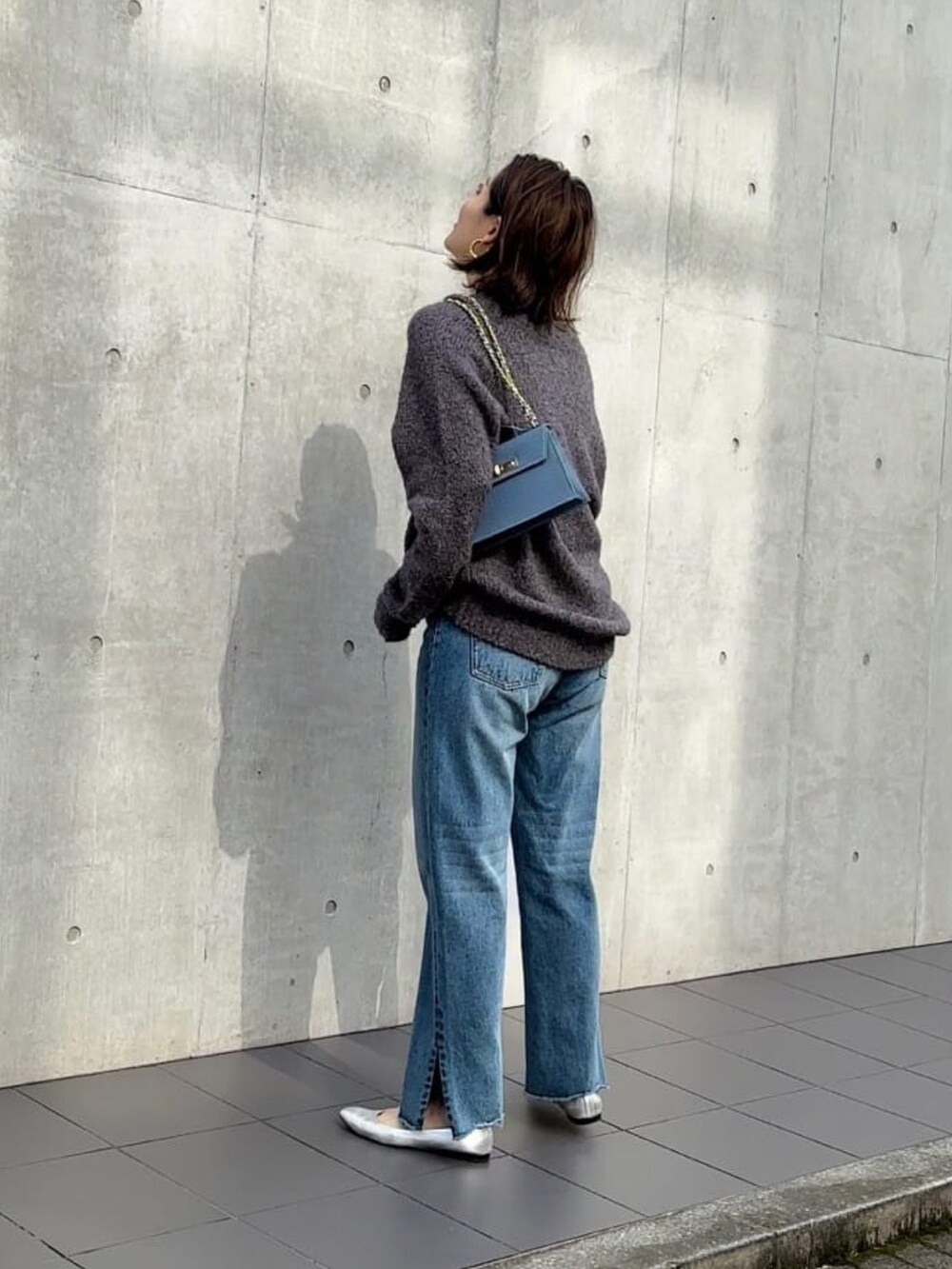 ブルー系のデニムパンツ、ブルー系のハンドバッグ、グレー系のニット/セーターを着用したレディースの秋コーディネートの4枚目の写真