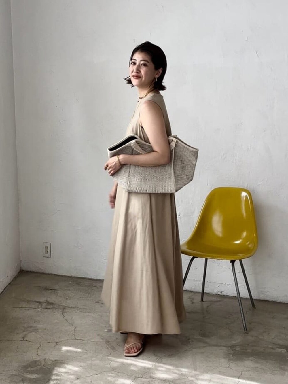 ベージュ系のワンピース、イエロー系のサンダルを着用したレディースの春コーディネートの2枚目の写真