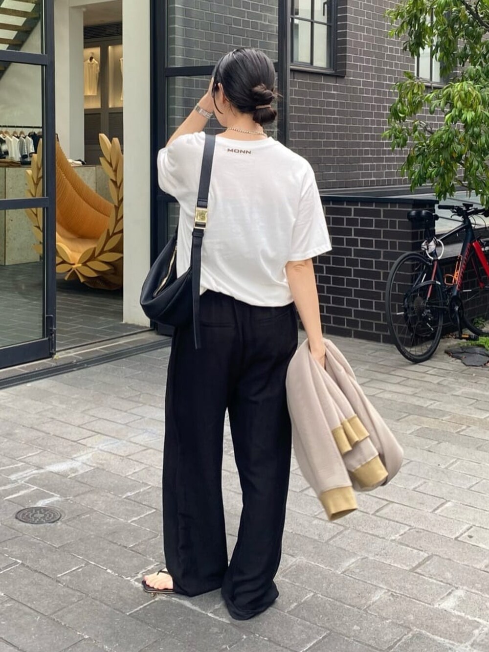 ブラック系のスラックス、ブラック系のサンダル、ブラウン系のTシャツ/カットソーを着用したレディースの夏コーディネートの3枚目の写真