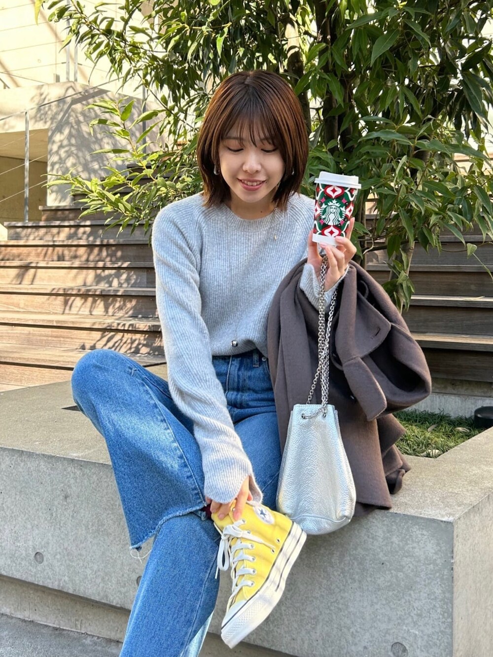 グレー系のニット/セーター、ブルー系のデニムパンツ、シルバー系のショルダーバッグを着用したレディースの冬コーディネートの2枚目の写真