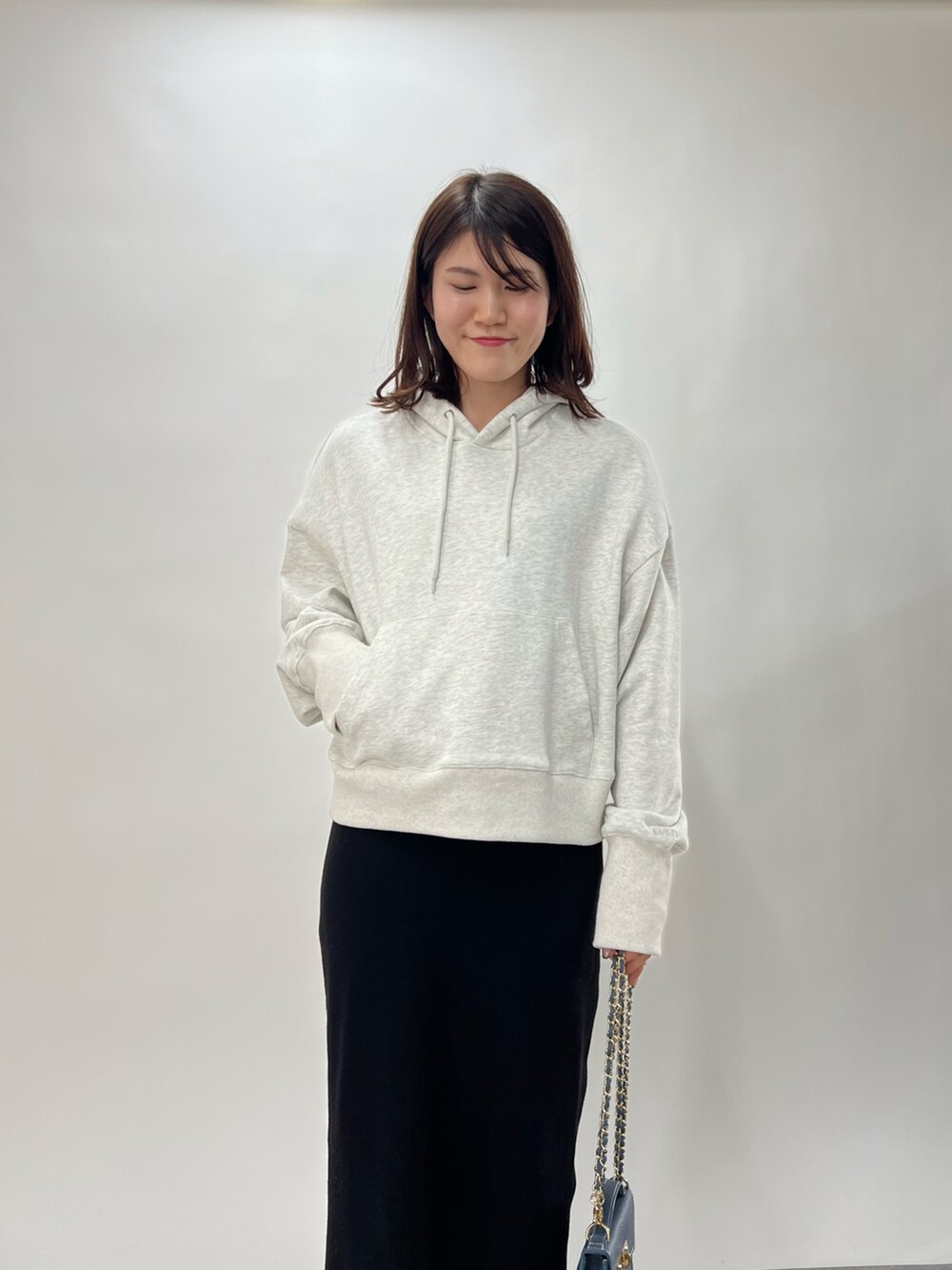 ブルー系のハンドバッグ、ブラック系のスカート、グレー系のパーカーを着用したレディースの冬コーディネートの2枚目の写真