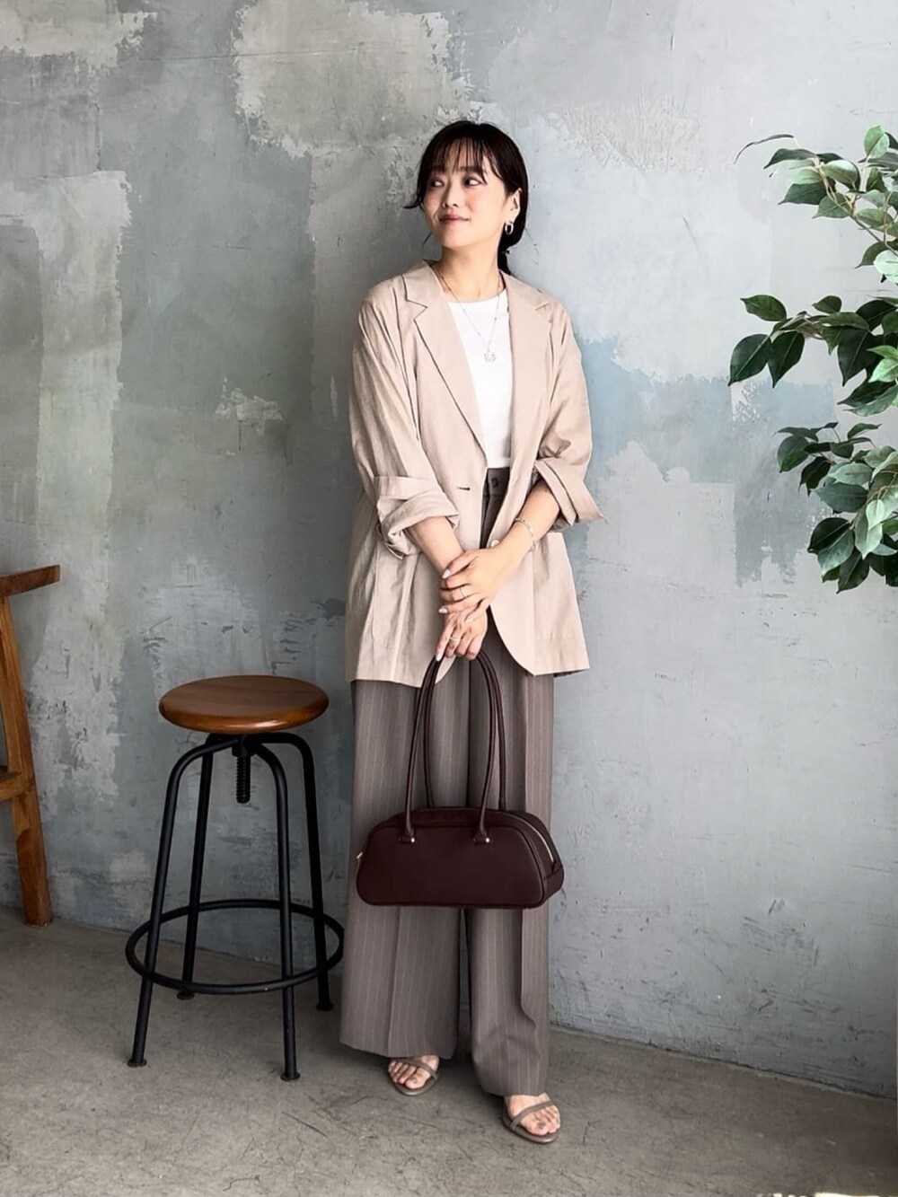 ベージュ系のテーラードジャケット、ブラウン系のショルダーバッグ、ベージュ系のスラックスを着用したレディースの夏コーディネートの4枚目の写真