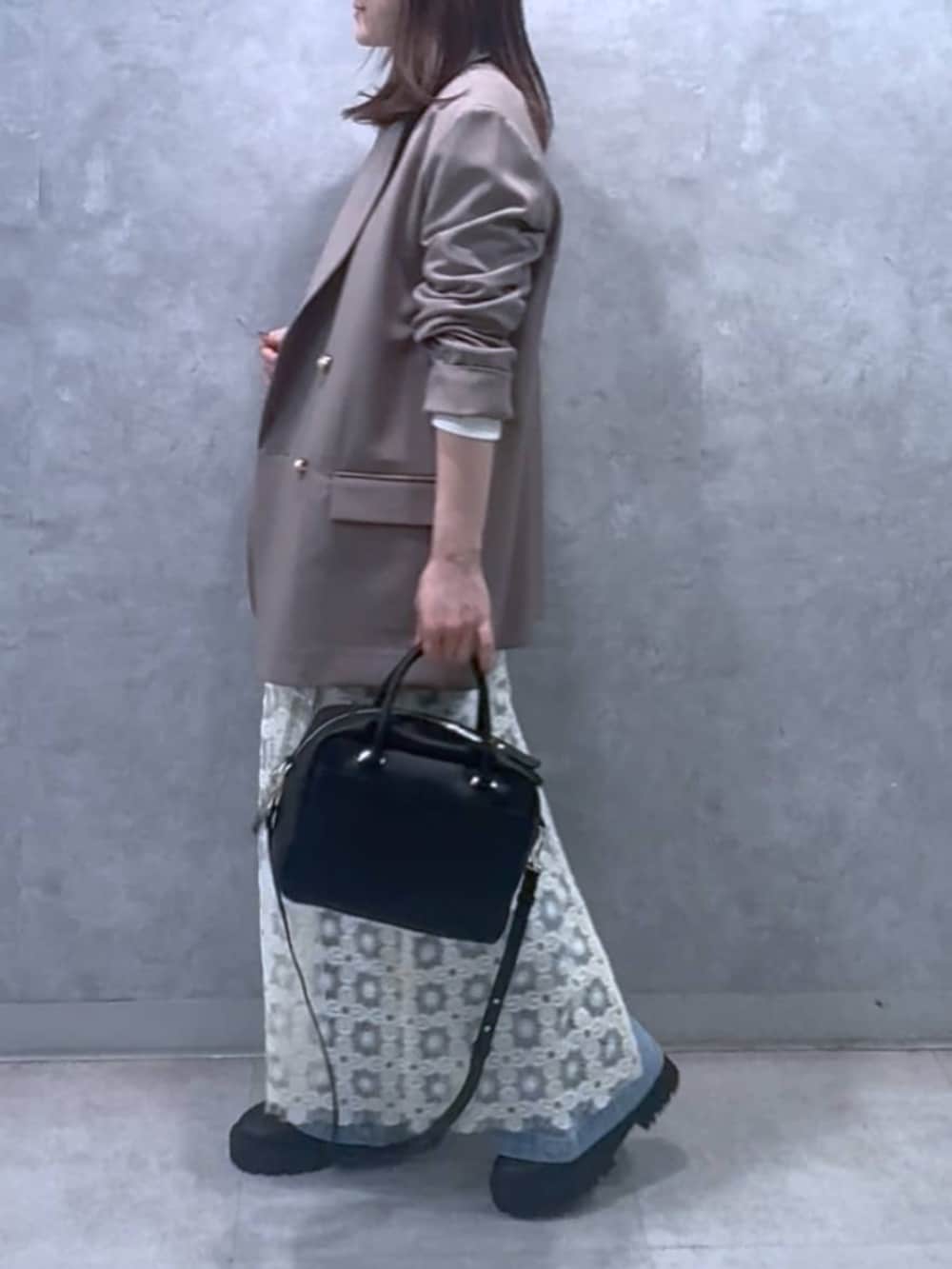 ホワイト系のスウェット、ブラウン系のテーラードジャケット、ブラック系のボストンバッグを着用したレディースの冬コーディネートの2枚目の写真