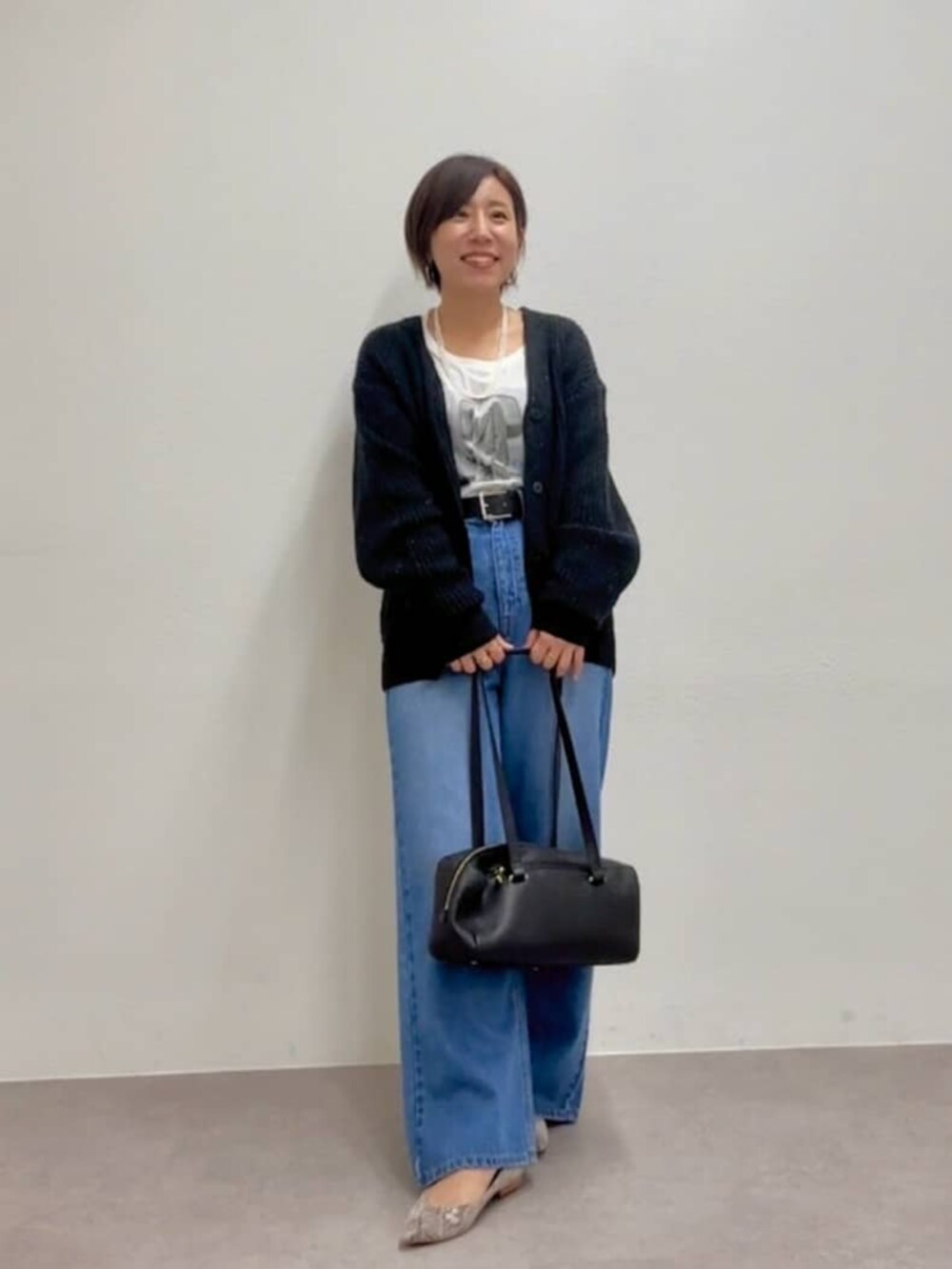 ブラック系のショルダーバッグ、グレー系のパンプス、ブルー系のデニムパンツを着用したレディースの秋コーディネートの3枚目の写真