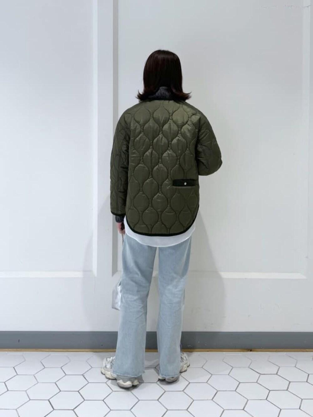 グリーン系のダウンジャケット/コート、グレー系のニット/セーター、ブルー系のデニムパンツを着用したレディースの秋コーディネートの3枚目の写真