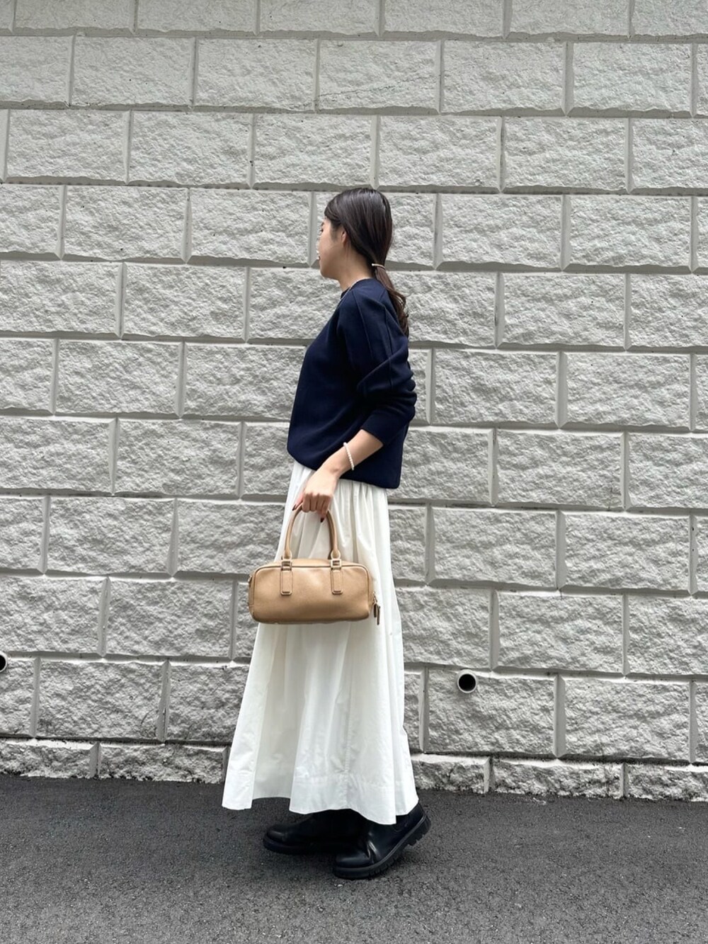 ホワイト系のスカート、ブルー系のニット/セーター、ブラック系のブーツを着用したレディースの秋コーディネートの3枚目の写真