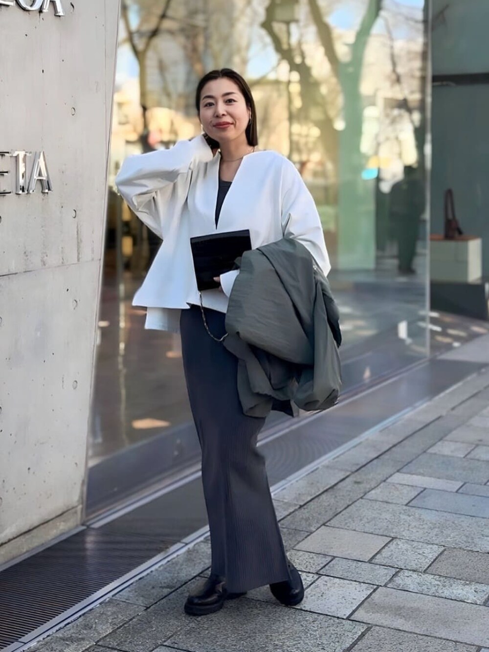 グレー系のワンピース、グリーン系のマウンテンパーカー、ブラック系のブーツを着用したレディースの冬コーディネートの4枚目の写真