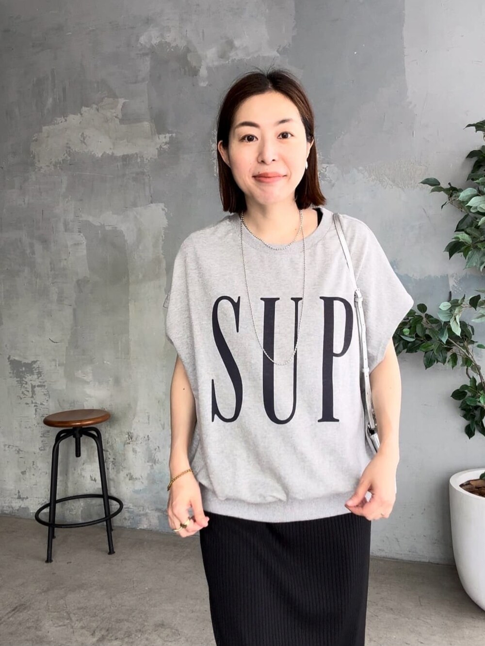 ブラック系のワンピース、ブラック系のサンダル、グレー系のTシャツ/カットソーを着用したレディースの春コーディネートの4枚目の写真