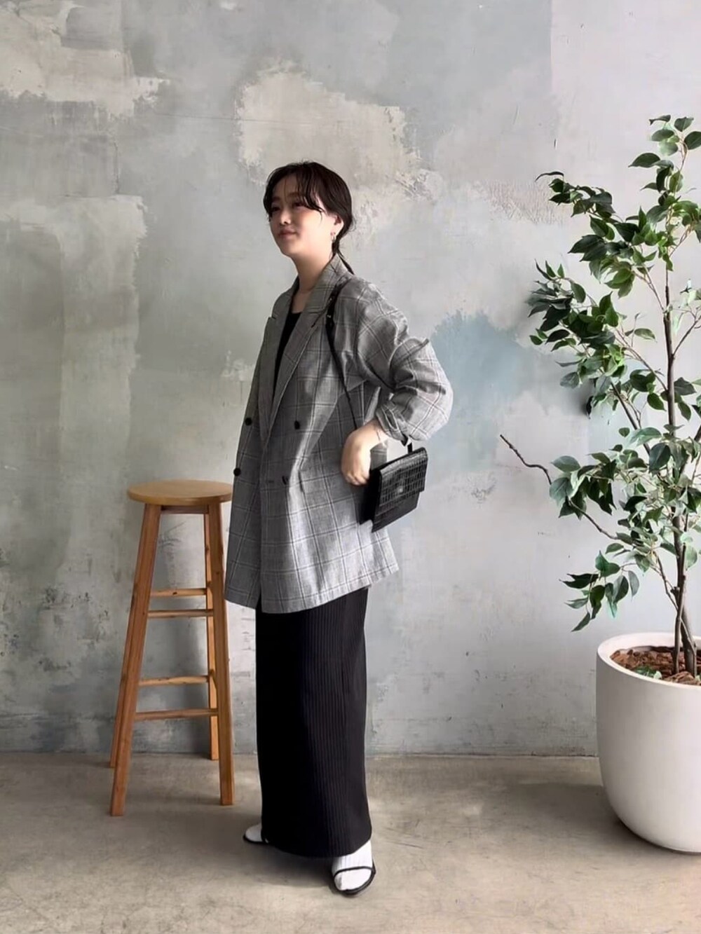 グレー系のテーラードジャケット、ブラック系のワンピース、ブラック系のサンダルを着用したレディースの春コーディネートの2枚目の写真