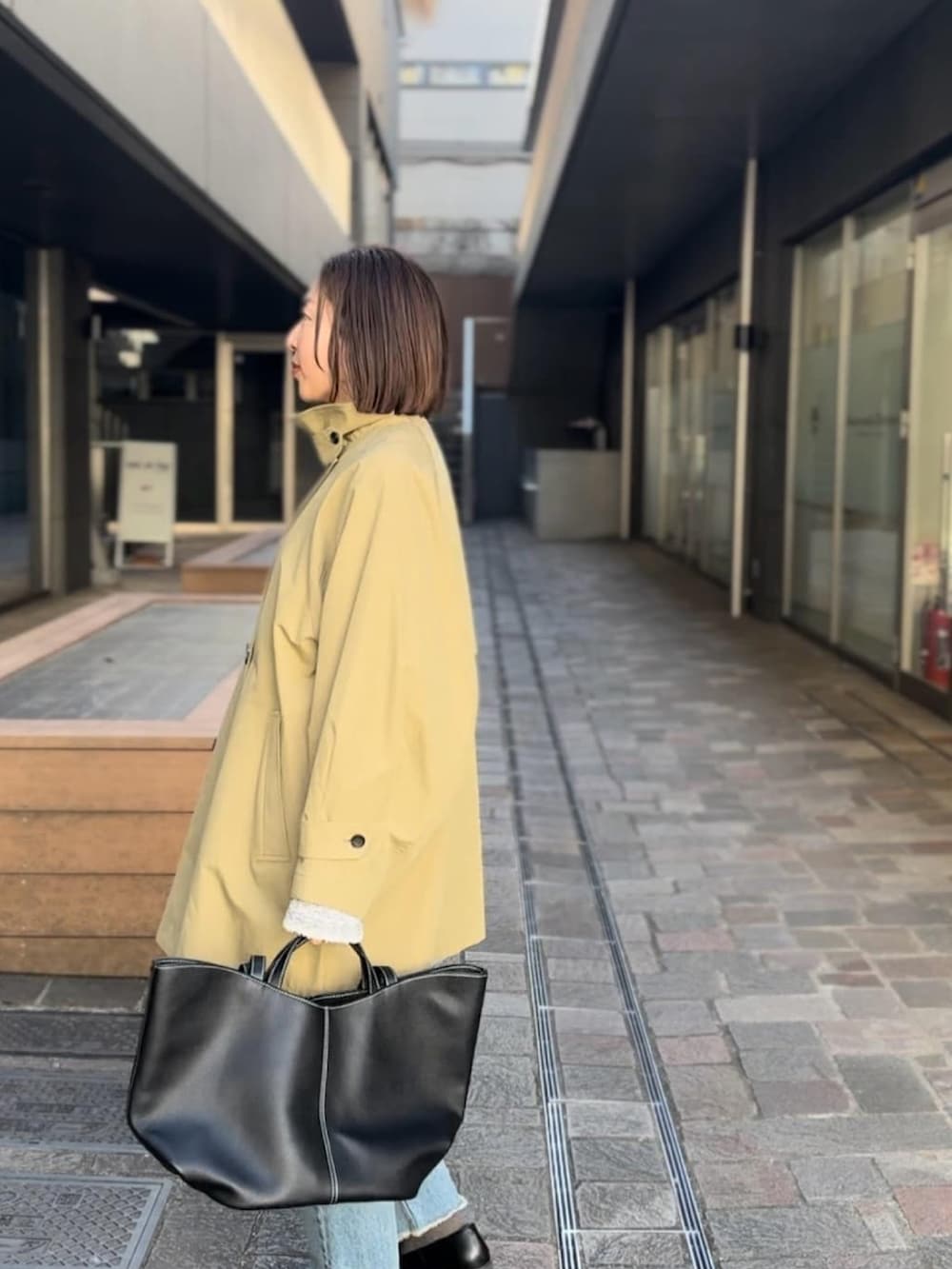 ベージュ系のトレンチコート、ブルー系のデニムパンツ、ブラック系のローファーを着用したレディースの冬コーディネートの4枚目の写真