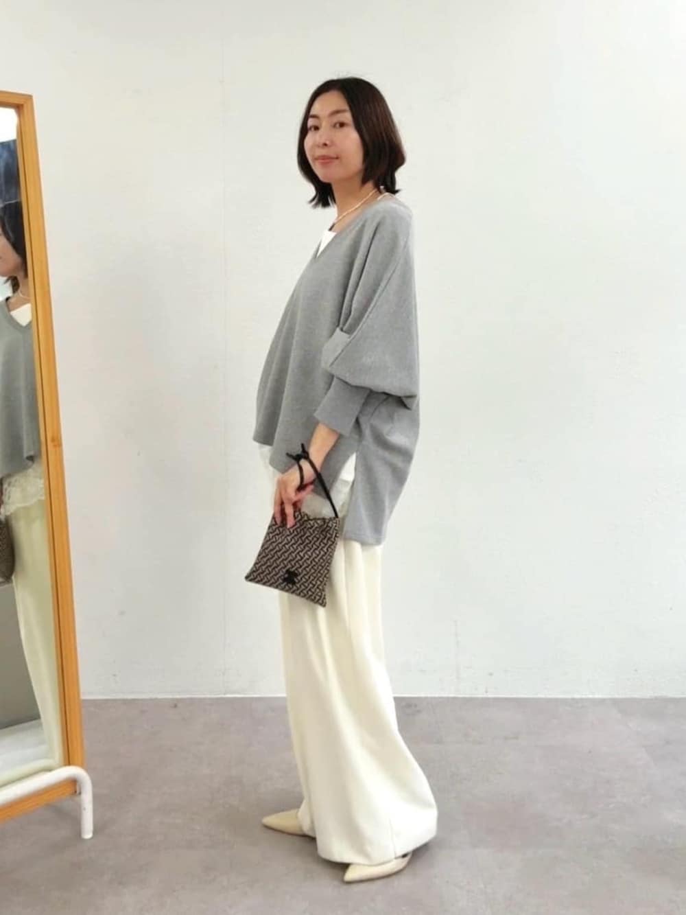 グレー系のスウェット、ホワイト系のスラックス、ホワイト系のキャミソールを着用したレディースの冬コーディネートの2枚目の写真