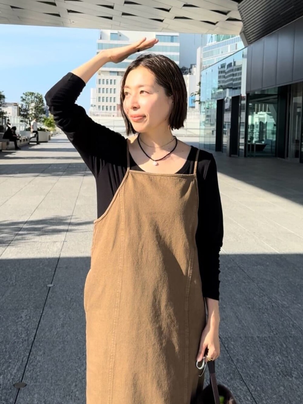 ブラウン系のワンピース、ブラック系のサンダル、ブラウン系のハンドバッグを着用したレディースの夏コーディネートの3枚目の写真