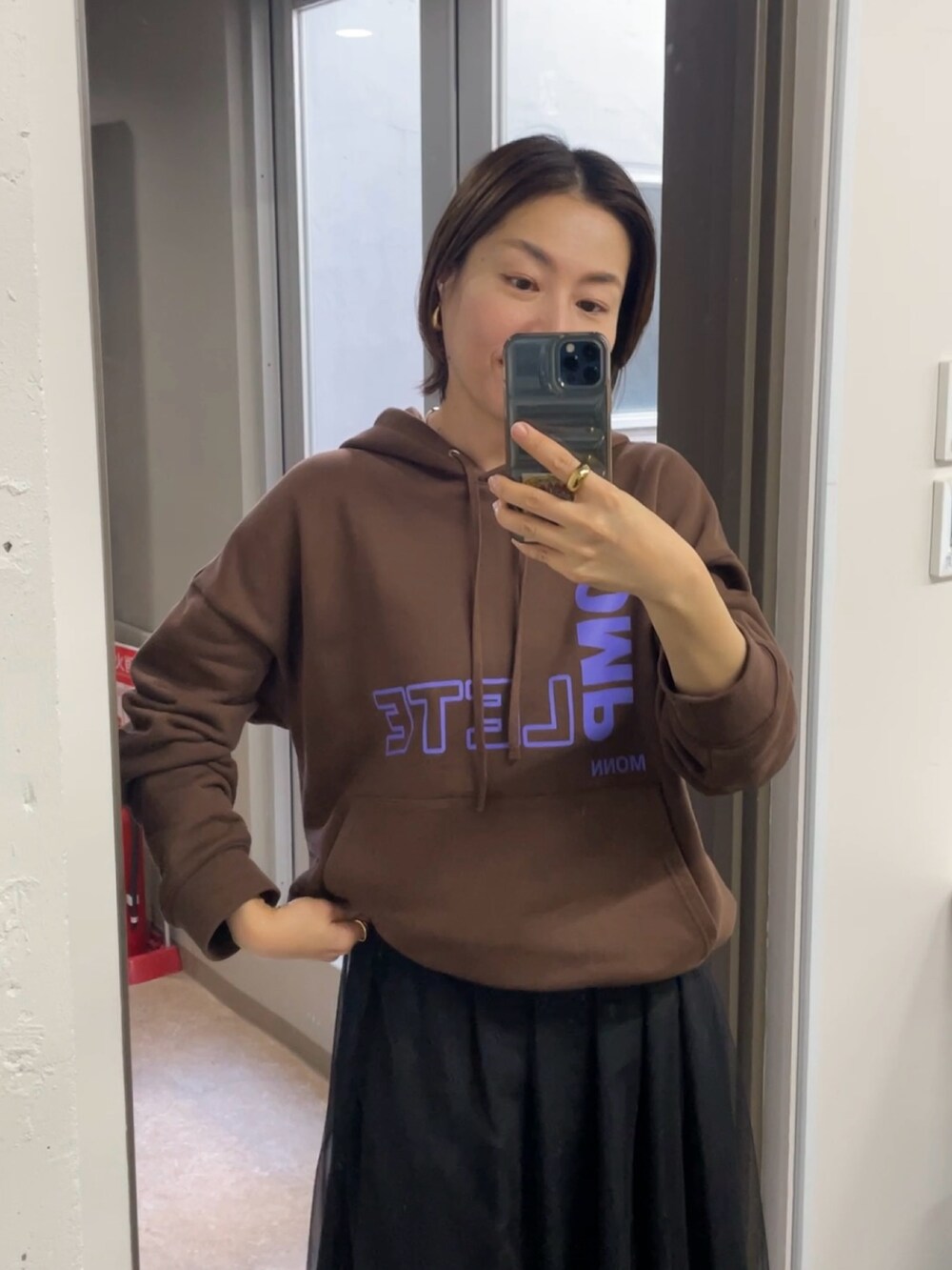 ブラック系のスカート、ブラウン系のパーカーを着用したレディースの秋コーディネートの3枚目の写真