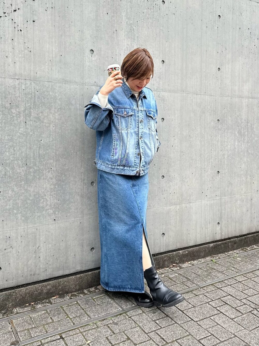 ブルー系のジャンパースカート、ブラック系のブーツを着用したレディースの冬コーディネートの3枚目の写真