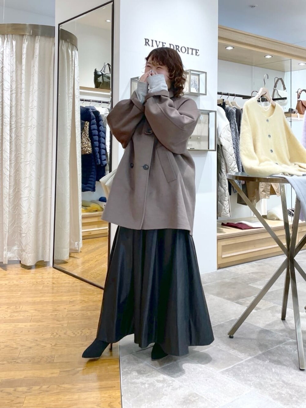 ブラウン系のその他アウター、ブラック系のスカート、ブラック系のブーツを着用したレディースの冬コーディネートの2枚目の写真