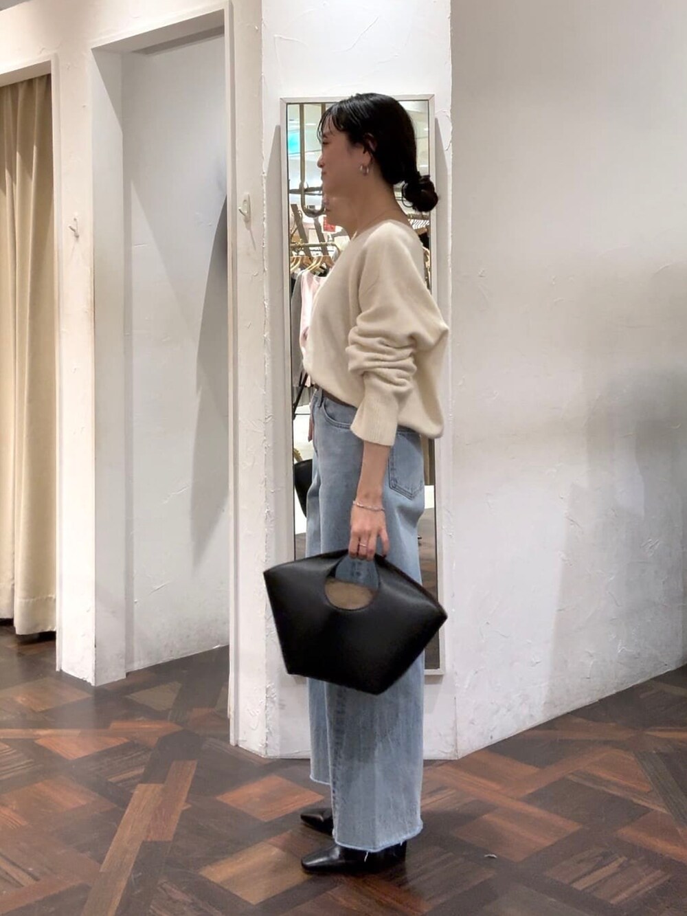 ホワイト系のニット/セーター、ブラック系のハンドバッグ、ブルー系のデニムパンツを着用したレディースの冬コーディネートの4枚目の写真