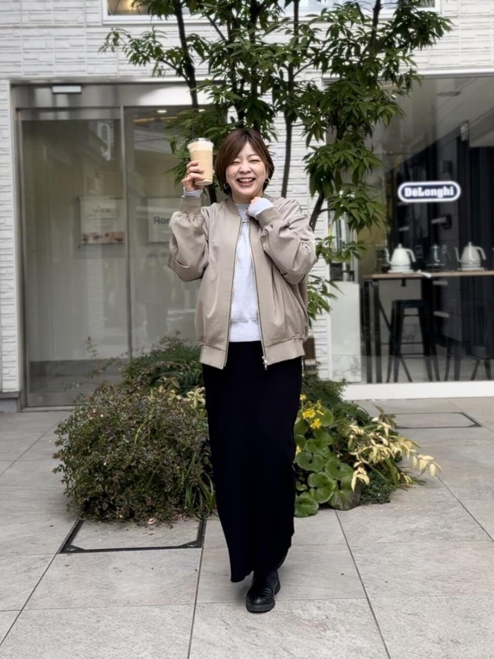 グリーン系のブルゾン、グレー系のニット/セーター、ブラック系のスカートを着用したレディースの春コーディネートの2枚目の写真