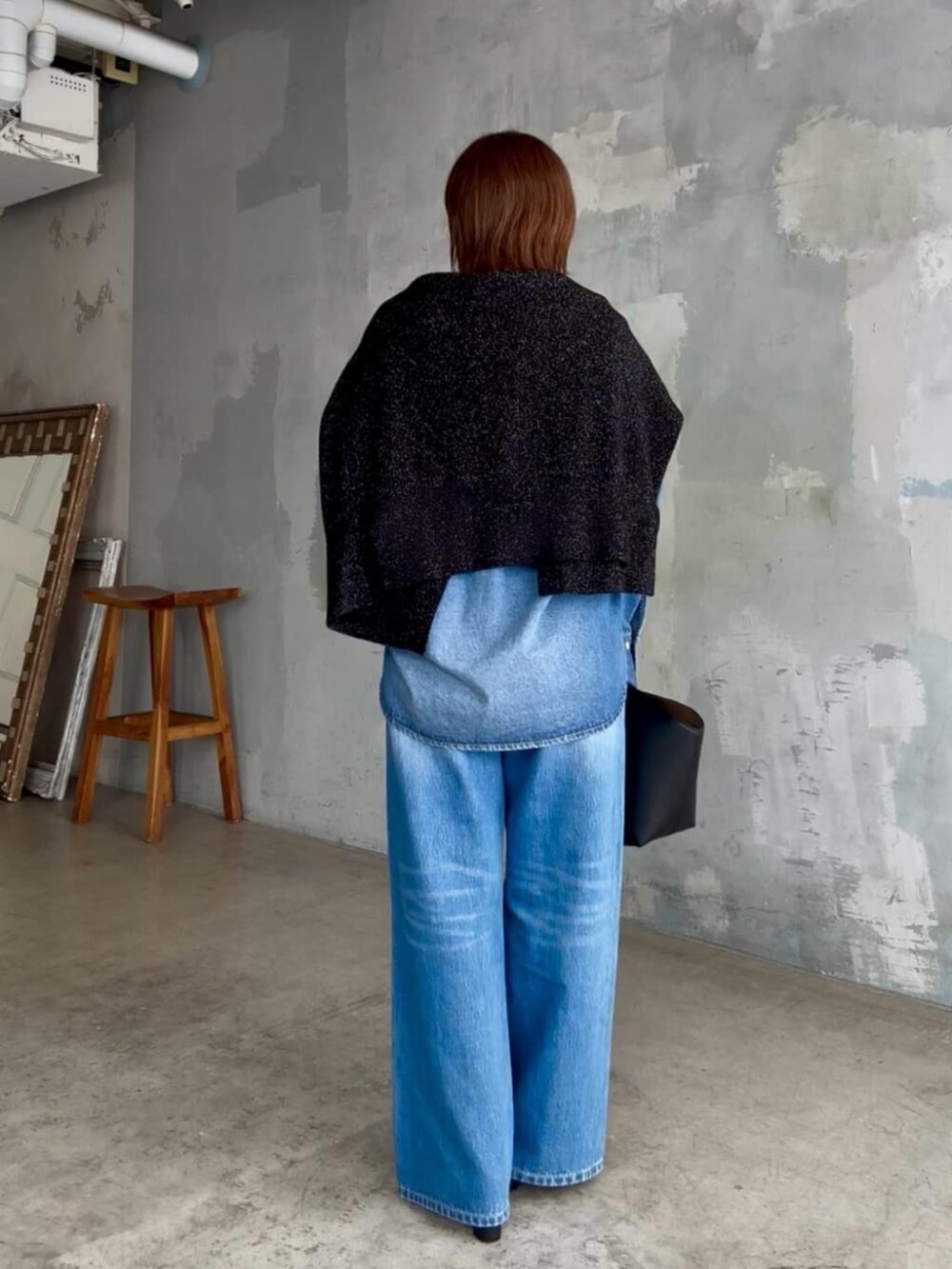 ブラック系のニット/セーター、ブルー系のシャツ/ブラウス、ブルー系のデニムパンツを着用したレディースの秋コーディネートの4枚目の写真