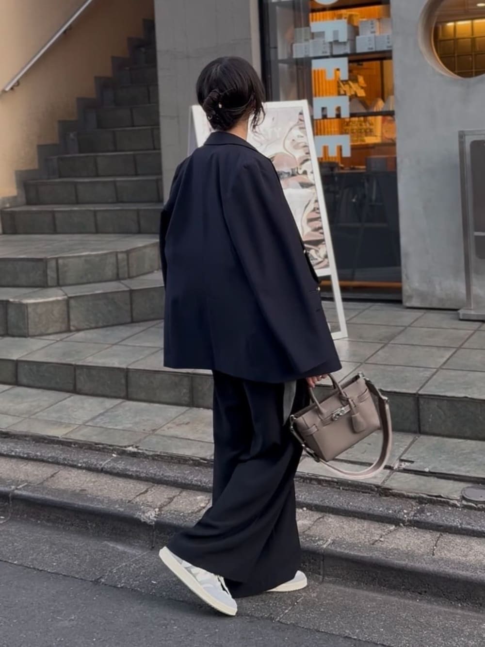 ブラック系のスラックス、グレー系のトートバッグ、ブルー系のテーラードジャケットを着用したレディースの冬コーディネートの2枚目の写真