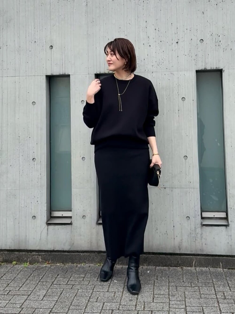 ブルー系のニット/セーター、ブルー系のスカート、ブラック系のショルダーバッグを着用したレディースの冬コーディネートの3枚目の写真