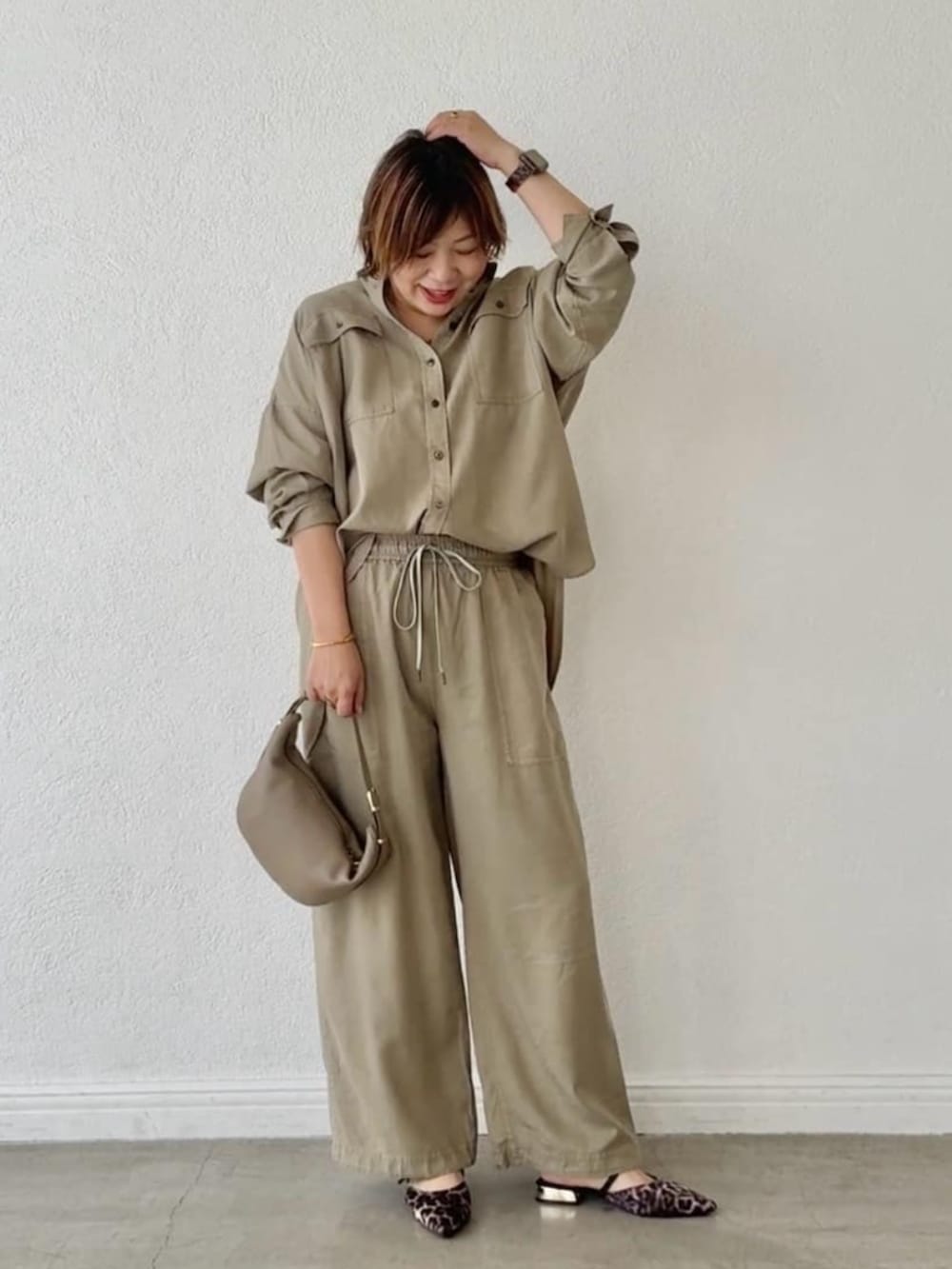 ベージュ系のその他シューズ、グリーン系のシャツ/ブラウス、ベージュ系のショルダーバッグを着用したレディースの春コーディネートの2枚目の写真