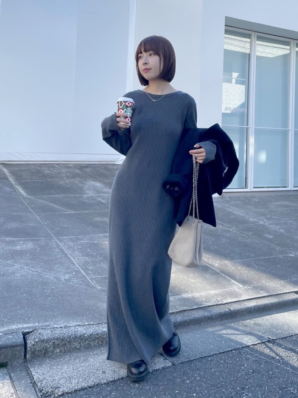 イエロー系のピーコート、グレー系のワンピース、ベージュ系のショルダーバッグを着用したレディースの冬コーディネートの5枚目の写真