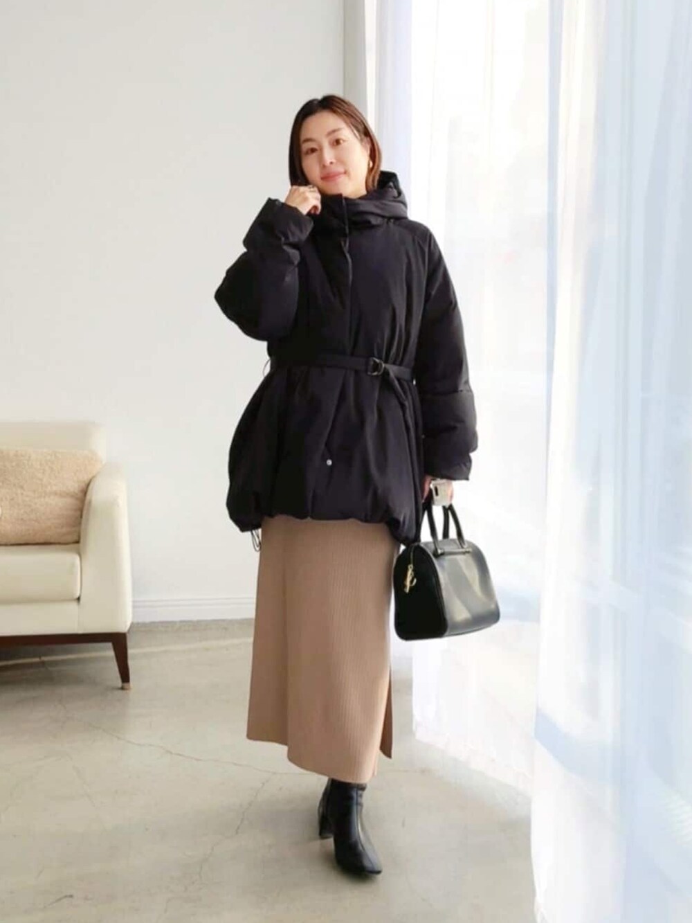 ブラック系のダウンジャケット/コート、ブラウン系のワンピース、ブラック系のブーツを着用したレディースの冬コーディネートの4枚目の写真