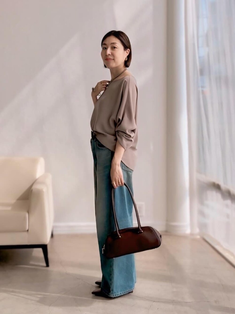 ブルー系のデニムパンツ、ブラウン系のショルダーバッグ、ブラウン系のローファーを着用したレディースの夏コーディネートの2枚目の写真