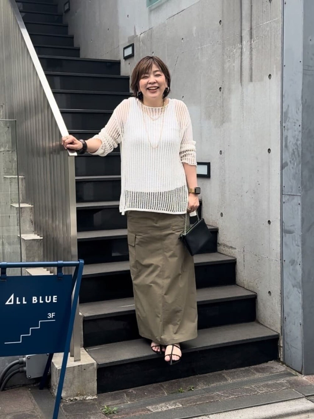 ホワイト系のニット/セーター、ブラック系のスカート、ブラック系のサンダルを着用したレディースの春コーディネートの2枚目の写真