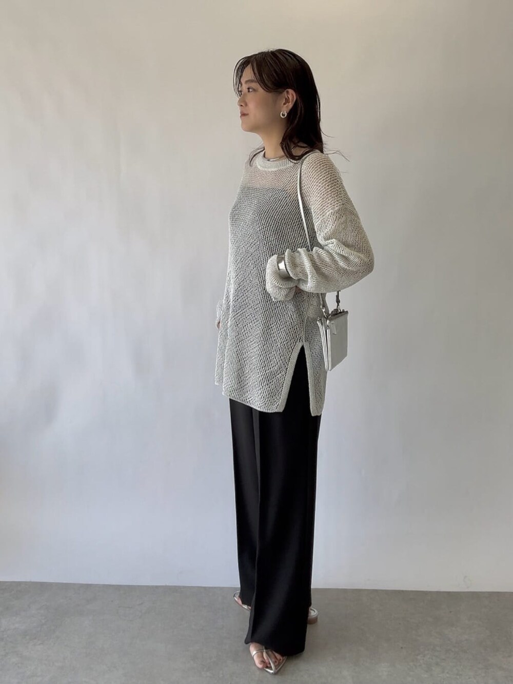 ブルー系のニット/セーター、グレー系のスラックスを着用したレディースの春コーディネートの4枚目の写真