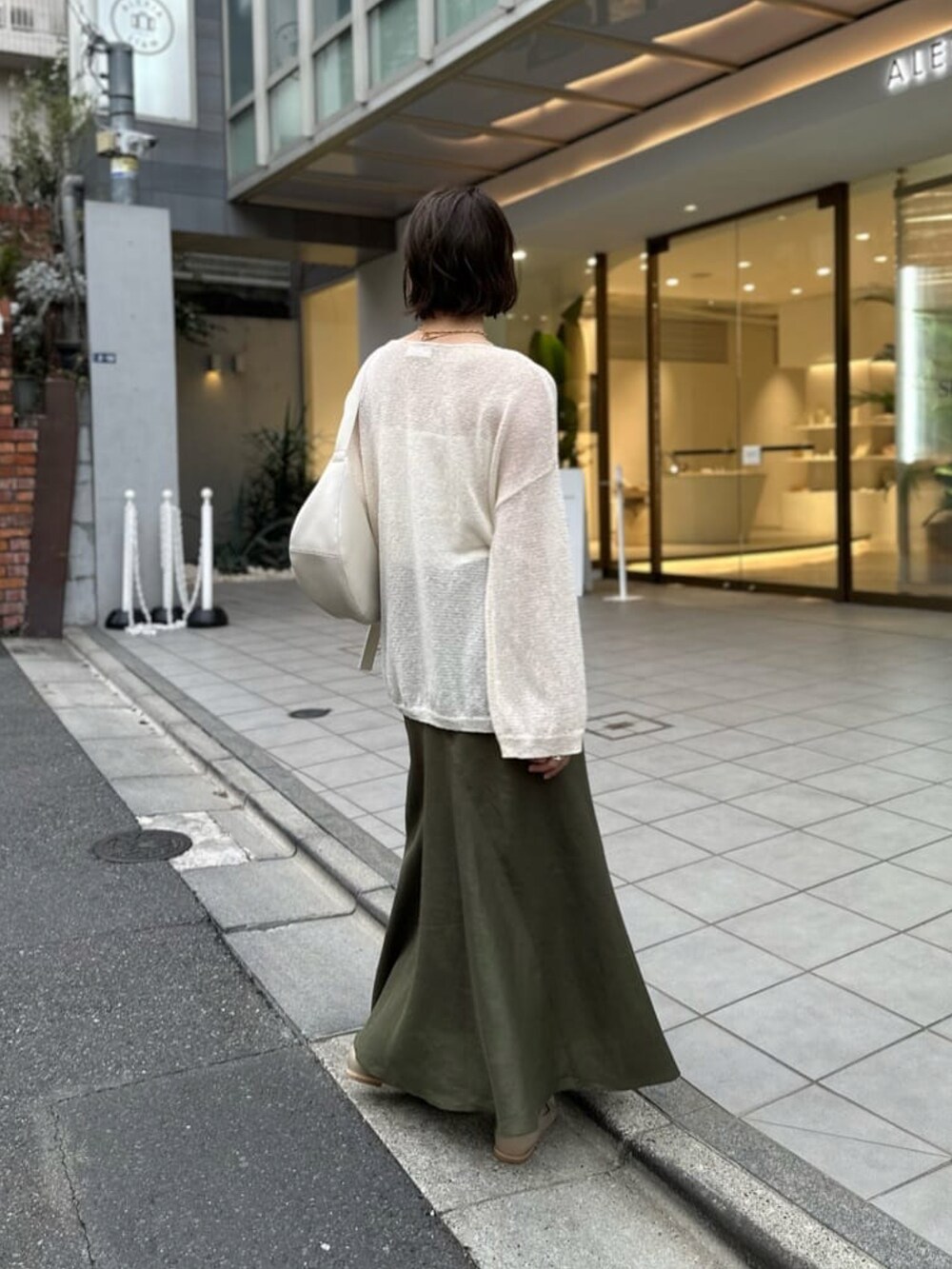 ホワイト系のニット/セーター、ホワイト系のキャミソール、グリーン系のスカートを着用したレディースの春コーディネートの4枚目の写真