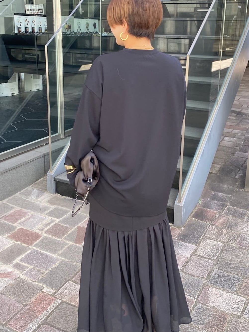 ブラック系のTシャツ/カットソー、ブラック系のスカート、ブラック系のショルダーバッグを着用したレディースの冬コーディネートの3枚目の写真